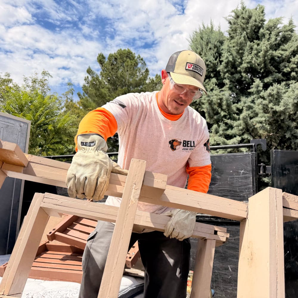 Bella crew member hauling a wooden furniture frame on a junk removal in Camp Verde job
